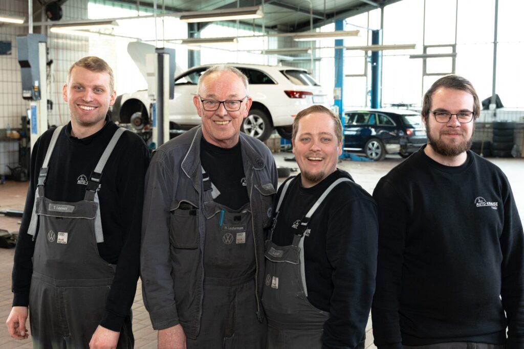 Vier Personen stehen in der Autohaus-Werkstatt.